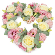 A generous heart-shaped floral tribute fills the scene, its soft colours and carefully layered textures creating a quiet sanctuary of flowers against a pure white background. The heart is fully formed and evenly balanced, its outline traced by clusters of blooms placed so close together that they appear to gently lean into one another, offering mutual support. Cream and light yellow roses form the main anchors, their velvety petals spiralling from tight centres into smooth, outward curves that catch some imagined soft daylight, much like the calm mornings over Loughton's green spaces near Roding Valley. Between these roses, pastel pink carnations are packed in clusters, their ruffled petals overlapping in subtle shades of blush that bring a comforting, almost quilt-like softness to the design. Deeper tones emerge in the mauve-pink lisianthus flowers scattered through the heart, their open, slightly flared blooms and delicate, paper-thin petals adding depth, grace, and a gentle sense of movement. Cool, silvery eucalyptus leaves wind naturally among the flowers, their rounded shapes and muted green hues providing a soothing backdrop and helping to define the heart's curved edges. Here and there, tiny yellow-green buds appear, like quiet reminders of new beginnings. The arrangement feels carefully considered and lovingly made, the sort of piece chosen to rest beside a casket, on a stand at a funeral service, or at a memorial gathering in Loughton, where family and friends come together to remember. This floral heart conveys enduring love, remembrance, and sympathy, offering a peaceful visual embrace during moments of grief.
